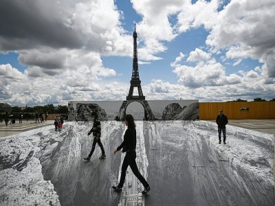 Des personnes marchent sur l'esplanade du Trocadéro, en face de la Tour Eiffel, sur un trompe-l'oeil de l'artiste  français de street-art JR, le 19 mai 2021 à Paris - Anne-Christine POUJOULAT [AFP]