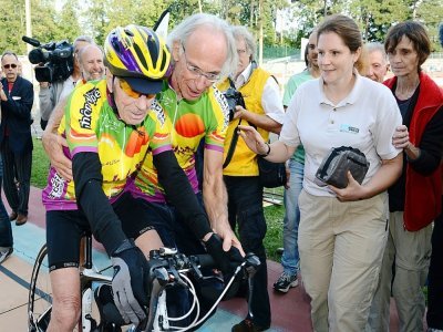 Le cycliste amateur français Robert Marchand (g), 100 ans, est aidé par son entraîneur Gérard Mistler (c), après avoir battu le record sur 100 km des plus de 100 ans, le 28 septembre 2012 au vélodrome de Lyon - PHILIPPE DESMAZES [AFP/Archives]