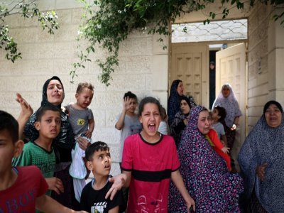 Des femmes et des enfants palestiniens sortent de leur maison pour aller dans un abri lors d'une frappe israélienne sur la ville de Gaza, le 20 mai 2021 - MOHAMMED ABED [AFP/Archives]