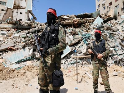 Des combattants masqués palestiniens devant les décombres d'un immeuble détruit par les bombardements israéliens dans la bande de Gaza, le 23 mai 2021 - Emmanuel DUNAND [AFP]
