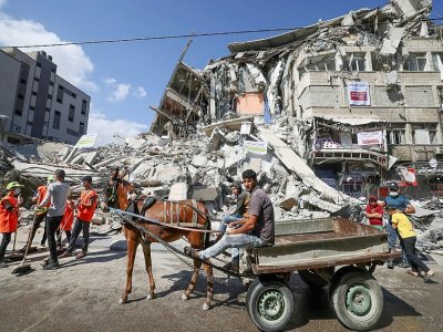 Des Palestiniens utilisent une charette pour transporter les gravats dans une rue de Gaza, le 23 mai 2021 - Emmanuel DUNAND [AFP]