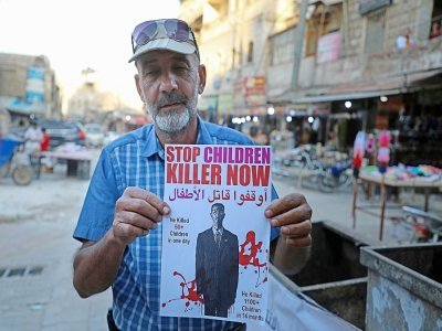 Un Syrien de la ville de Dana (est de la Syrie) brandit une affiche dénonçant le président Bachar al-Assad comme un tueur, le 24 mai 2021. - AAREF WATAD [AFP]