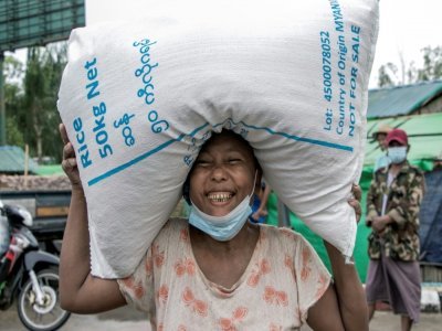 Une femme porte un sac de riz distribué par le PAM à Rangoun le 21 mai 2021 - STR [AFP]