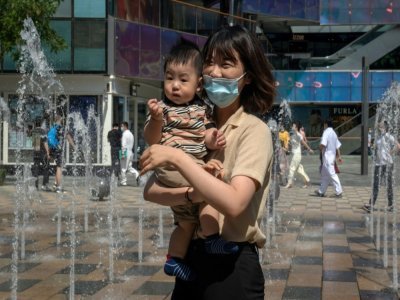 Une mère et son enfant devant un centre commercial de Pékin, le 1er juin 2021 en Chine - NICOLAS ASFOURI [AFP]