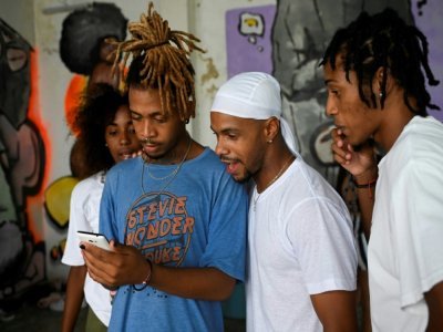 Des danseurs de la compagnie de hip hop Datway regardent une vidéo sur un smartphone dans un studio de La Havane, le 21 mai 2021 à Cuba - YAMIL LAGE [AFP]