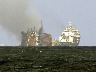 Un bateau de la société néerlandaise Smit remorque le porte-conteneurs MV X-Press Pearl (g), ravagé par un incendie depuis douze jours, pour l'éloigner des côtes de Colombo, le 2 juin 2021 au Sri Lanka - ISHARA S. KODIKARA [AFP]