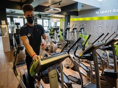 Un employé d'une salle de fitness nettoie ses machines, deux jours avant la réouverture des salles de sport, le 7 juin 2021 à Strasbourg - PATRICK HERTZOG [AFP]