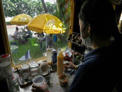 Une employée prépare des boissons dans un wagon de train transformé en café, le 31 mai 2021 à Phnom Penh, au Cambodge - TANG CHHIN Sothy [AFP]