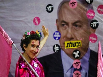 Une Israélienne fait un geste de la main devant un portrait de Benjamin Netanyahu lors d'une manifestation contre le Premier ministre sortant à Jérusalem, le 12 juin 2021 - Emmanuel DUNAND [AFP]