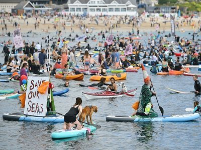 Des écologistes manifestent sur des planches de surf, paddles et kayaks à Falmouth (Cornouailles) en marge du sommet du G7 le 12 juin 2021 - Oli SCARFF [AFP]