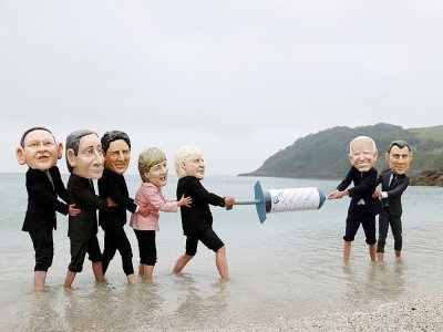 Des militants avec des masques à l'effigie des dirigeants du G7 se disputent une seringue de vaccin contre le Covid-19 lors d'une action menée par Oxfam, à Falmouth, le 11 juin 2021 - Adrian DENNIS [AFP]