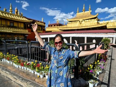 Une touriste posant devant le temple du Jokhang à Lhassa, le 1er juin 2021 - Hector RETAMAL [AFP]