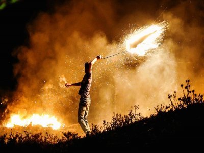 Un manifestant palestinien lance un projectile en direction des forces israéliennes lors d'une manifestation dans l'est de Gaza le 15 juin 2021 - Mahmud hams [AFP]