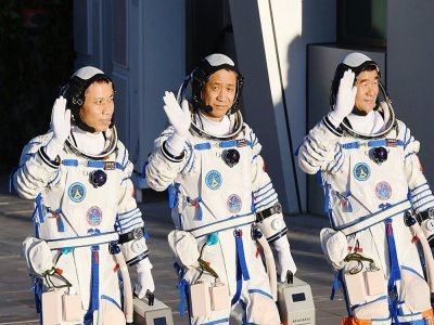 Les astronautes chinois Nie Haisheng (c), Liu Boming (d) et Tang Hongbo salue la foule avant leur décollage à bord de la fusée Longue-Marche 2F au Centre de lancement spatial de Jiuquan, le 17 juin 2021 en Chine - GREG BAKER [AFP]