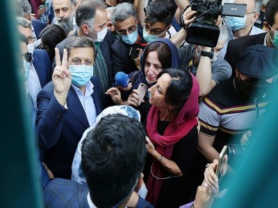 Abdolnasser Hemmati (L), un candidat à la présidentielle en Iran, fait le V de la victoire devant un bureau de vote à Téhéran, le 18 juin 2021 - ATTA KENARE [AFP]