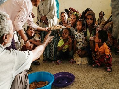 Des habitants ayant fui les violences dans la région du Tigré, en Ethiopie, partagent le seul repas de la journée dans une ancienne classe d'école transformée en abri de fortune, à Mekele, le 19 juin 2021 - Yasuyoshi CHIBA [AFP]