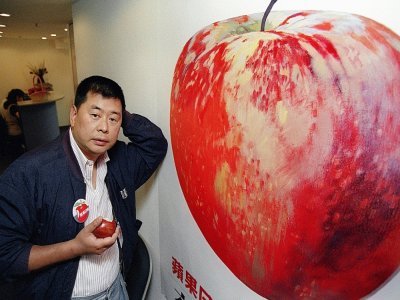 Le magnat de la presse et fondateur d'Apple Daily, Jimmy Lai, posant devant une affiche de pomme, à Hong Kong, le 14 juin 1995 - Mike CLARKE [AFP/Archives]