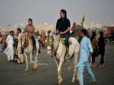 Des femmes en promenade à cheval à Karachi, au Pakistan, le 13 juin 2021 par une journée chaude d'été - Rizwan TABASSUM [AFP]
