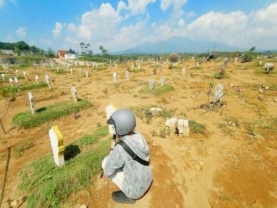 Un homme sur la tombe d'un proche dans un cimetière pour les victimes du Covid-19 à Semarang, en Indonésie, le 30 juin 2021 - Daffa Ramya Kanzuddin [AFP]
