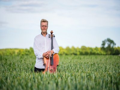 Le violoncelliste Jacob Shaw avec son violon dans un champ de maïs à Stevns, le 15 juin 2021 - Jonathan NACKSTRAND [AFP]