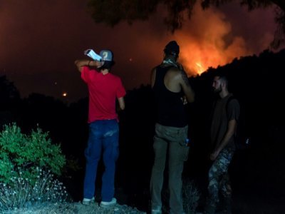 Des villageois de Vavatsinia regardent l'incendie qui ravage les collines proches de Larnaca,  le 3 juillet 2021 - Iakovos Hatzistavrou [AFP]