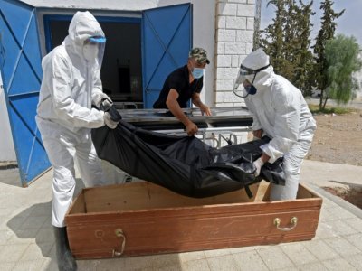 Des employés municipaux mettent le corps d'une victime du Covid-19 dans un cercueil dans un hôpital de Kairouan, en Tunisie, le 4 juillet 2021 - FETHI BELAID [AFP]