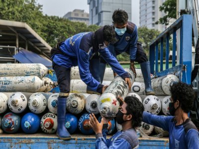 Des employés déchargent des bonbonnes d'oxygène dans une station de distribution d'urgence à Jakarta, le 5 juillet 2021 - Mariana [AFP]