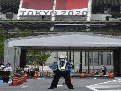 Un garde de sécurité sur une route menant au stade national, lieu principal des Jeux olympiques et paralympiques de Tokyo 2020, à Tokyo, le 7 juillet 2021 - Kazuhiro NOGI [AFP]