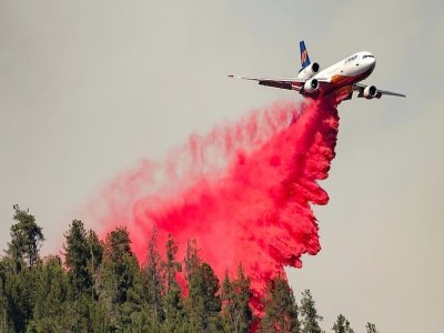 Un avion bombardier d'eau largue du "retardant", un produit coloré (rouge) qui revêt la végétation d'une pellicule ignifuge,  le long d'une crête pendant un incendie à Lakehead, en Californie, le 2 juillet 2021 - JOSH EDELSON [AFP/Archives]
