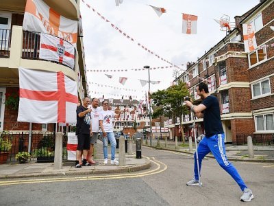 Des habitants d'une résidence dans le sud de Londres, entourés de drapeaux d'Angleterre, le 10 juillet 2021 à la veille de la finale de l'Euro 2020 contre l'Italie - JUSTIN TALLIS [AFP]