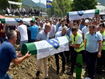 Des musulmans bosniaques mettent en terre des  cercueils contenant les restes de victimes du massacre de Srebrenica en 1995, dans le mémorial de Potocari le 11 juillet 2021 - ELVIS BARUKCIC [AFP]