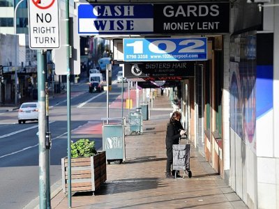 Une femme devant un magasin fermé à Fairfield, dans la banlieue de Sydney, le 12 juillet 2021 - Saeed KHAN [AFP]