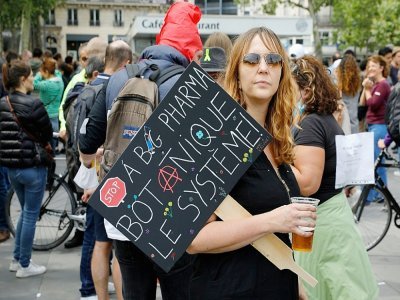 Une femme porte une pancarte hostile aux entreprises pharmaceutiques alors qu'elle participe à un rassemblement place de la République à Paris le 14 juillet 2021 pour protester contre une décision gouvernementale d'imposer des tests Covid-19 aux pers - GEOFFROY VAN DER HASSELT [AFP]