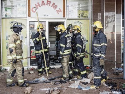 Les pompiers sud-africains devant un centre commercial dévalisé à Vosloorus, dans la banlieue de Johannesburg, Afrique du Sud, le 14 juillet 2021 - MARCO LONGARI [AFP]