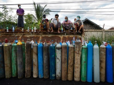 Des gens attendent pour remplir des bouteilles d'oxygène pour leurs proches atteints de Covid-19, à Mandalay le 13 juillet 2021 - STR [AFP]