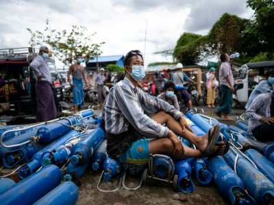 Un homme assis fait la queue pour remplir des bouteilles d'oxygène à Mandalay le 13 juillet 2021 - STR [AFP]