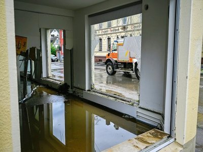 Un camion de pompiers passe devant un bâtiment inondé et aux vitres brisés par les fortes intempéries à Dahl, près de Hagen, dans l'ouest de l'Allemagne, le 15 juillet 2021 - SASCHA SCHUERMANN [AFP]