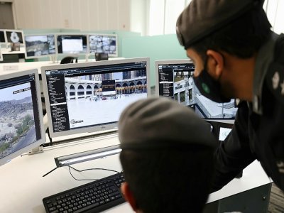 Des membres des forces de sécurité regardent des images de caméras de surveillance installées sur les sites du grand pèlerinage de La Mecque, le 16 juillet 2021 en Arabie saoudite - Fayez Nureldine [AFP]
