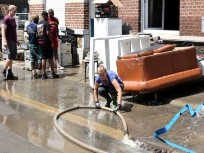 Un habitant pompe l'eau près d'une maison endommagée à Angleur, près de Liège, le 17 juillet 2021 - François WALSCHAERTS [AFP]