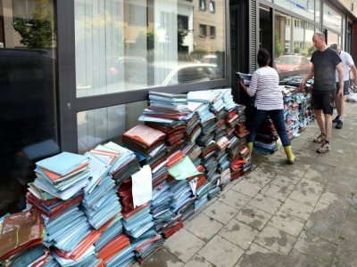 Des habitants nettoient un bureau endommagé à Angleur, près de Liège, le 17 juillet 2021 - François WALSCHAERTS [AFP]