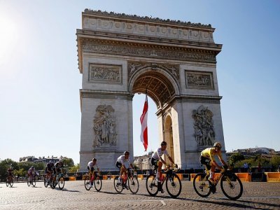 Le Slovène Tadej Pogacar (d) devant l'Arc de Triomphe lors de la 21e et dernière étape du Tour de France, entre Chatou et Paris, le 18 juillet 2021 - Thomas SAMSON [AFP]