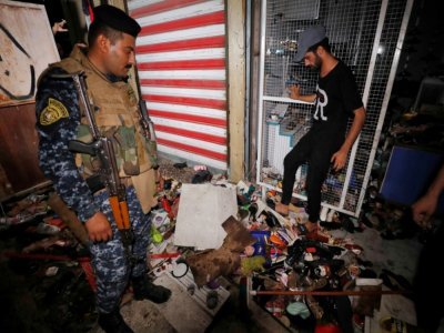 Des Irakiens inspectent les dégâts dans un marché de Bagdad après un attentat meurtrier, le 19 juillet 2021 - AHMAD AL-RUBAYE [AFP]