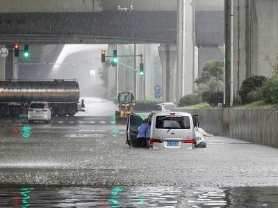 Des habitants de Zhengzhou poussent leur voiture, dans la ville inondée après des orages violents, le 20 juillet 2021 - STR [AFP]