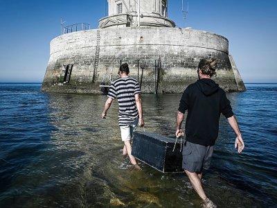 Les gardiens Thomas Dalisson (g) et Nicolas Quezel-Guerraz transportent une caisse de ravitaillement pour la relève avant de quitter le phare du Cordouan, le 11 juin 2021 au Verdon-sur-Mer, en Gironde - Philippe LOPEZ [AFP]