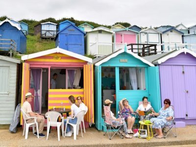 Des personnes assises devant des cabines de plage, le 15 juillet 2021à  Walton-on-the-Naze - Justin TALLIS [AFP]