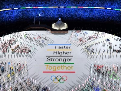 La devise des Jeux Olympiques "Plus vite, plus haut, plus fort" est projetée au milieu des délégations de sportifs du monde entier, lors de la cérémonie d'ouverture des Jeux Olympiques, le 23 juillet 2021 à Tokyo - François-Xavier MARIT [AFP]