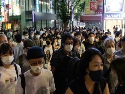 Une foule masquée marche dans le districk de Shinjuku, le 17 juillet 2021 à Tokyo - Yuki IWAMURA [AFP/Archives]