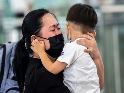Une femme dit adieu à un jeune enfant à l'aéroport de Hong Kong le 19 juillet 2021 - ISAAC LAWRENCE [AFP]