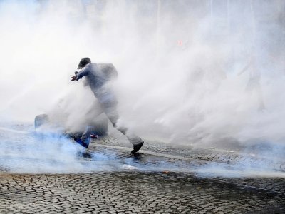 Un manifestant entouré de gaz lacrymogène court lors de heurts au cours d'une manifestation anti-pass sanitaire le 24 juillet 2021 à Paris - Alain JOCARD [AFP]