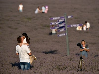 Des touristes visitent et se photographient dans un champ de lavande, à Valea-Trestieni, en Moldavie, le 10 juillet 2021 - SERGEI GAPON [AFP]